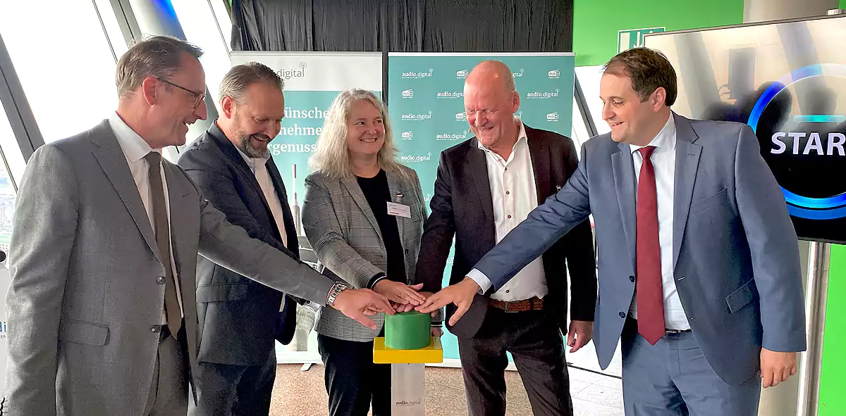 Start multipleksu na wysokości ok. 170 metrów w wieży telewizyjnej Rheinturm w Düsseldorfie. dr. Tobias Schmid, dyrektor Landesanstalt für Medien NRW; Michael Radomski, prezes UPLINK Network; Martina Rutenbeck, prezes DIVICON MEDIA; Arnold Stender, prezes audio.digital NRW; Nathanael Liminski, szef kancelarii stanu kraju związkowego Nadrenia Północna-Westfalia.